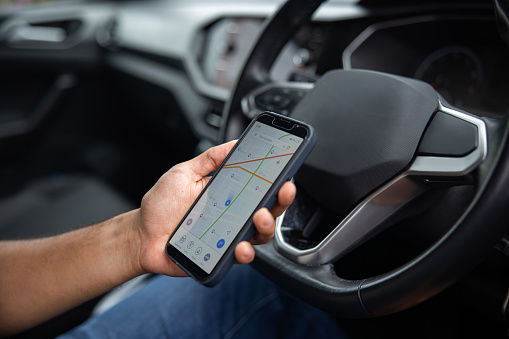 Close-up on an English man using a GPS app on a cell phone while driving a car - lifestyle concept