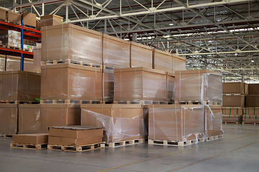 A warehouse filled with lots of boxes and boxes stacked on top of each other, a Logistics warehouse. Spacious component part with boxes. Industrial building with goods on pallets. Cardboard boxes are stacked on top of each other