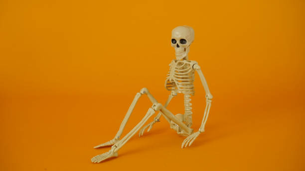 istock Sitting skeleton on a yellow background. 1580852774