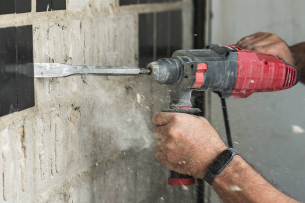 istock Builder with a puncher dismantles old tiles from a concrete wall 1580874915
