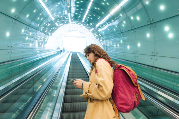 istock Woman using smartphone on the escalator 1580891260