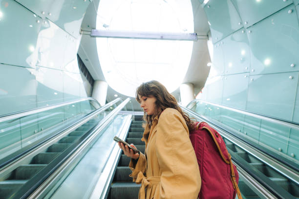 istock Woman using smartphone on the escalator 1580891264