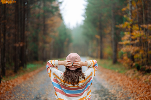 a young teenage girl walks in the autumn forest, goes along the road and enjoys the beautiful nature and bright yellow leaves