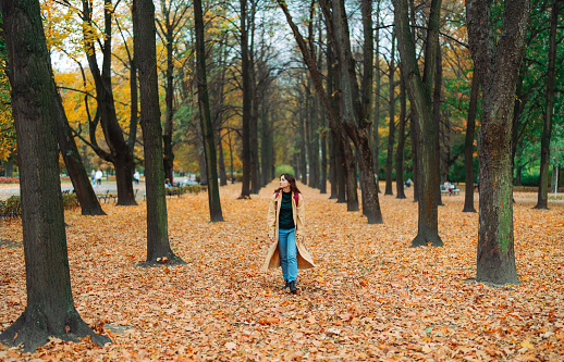 Young  woman with backpack walking in the park in autumn and enjoying serenity