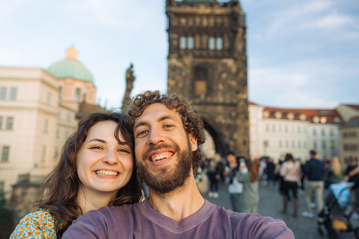 Selfie of  cheerful woman and man on Karl bridge in Prague