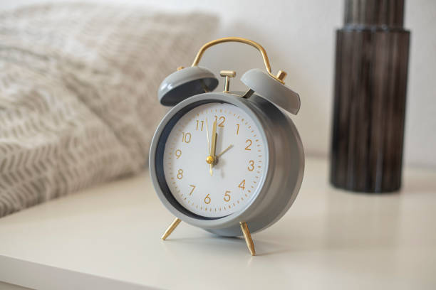 istock Retro alarm clock stands on a white bedside table near the bed 1580946808