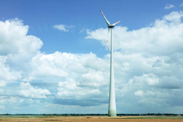 Horizontal axis wind turbine in the field under the cloudy blue sky, electrical power green production