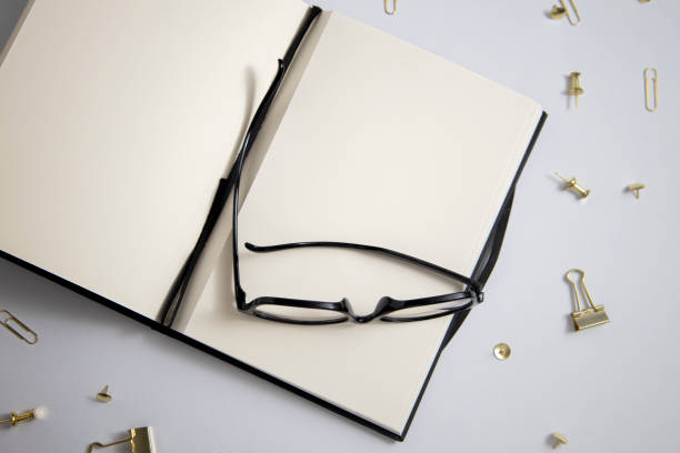 istock Open diary, glasses, gold paper clips, paper clips on a white background. Top view, flat lay 1580951366