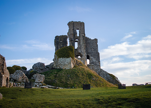Corfe Castle is a fortification standing above the village of the same name on the Isle of Purbeck peninsula in the English county of Dorset. Built by William the Conqueror, the castle dates to the 11th century and commands a gap in the Purbeck Hills on the route between Wareham and Swanage.