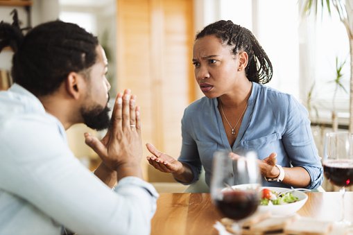 Angry African American woman arguing with her husband during lunch at home