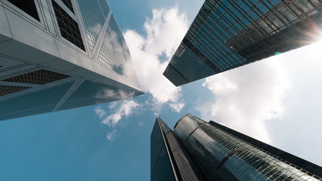 Time lapse of skyscraper, cloud on sunny sky, corporate business building in Hong Kong central financial district. Low angle view. Enterprise organisation, Asia economy, office people job work concept