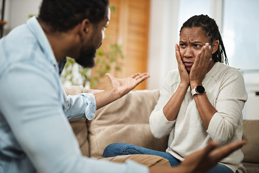 Angry African American couple arguing on sofa in the living room