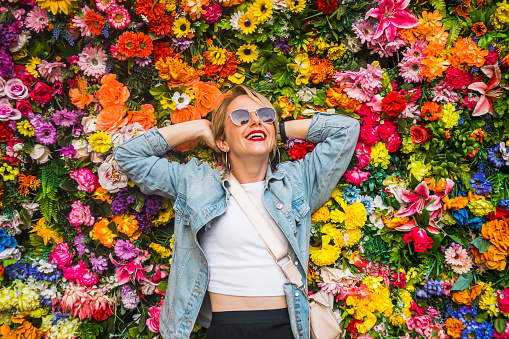 Portrait of beautiful woman smiling in front of flower wall