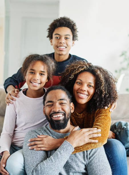 child family mother portrait father woman happy daughter son man girl female black american african love together boy fun parent teen teenager Portrait of a happy black family mother father and kids at home on couch black african girls pictures stock pictures, royalty-free photos & images