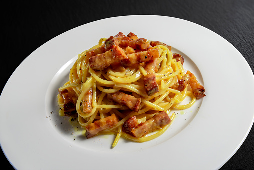 Dish with spaghetti carbonara isolated on black stone