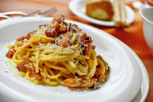 тарелка со спагетти карбонара на накрытый стол - parmesan cheese cheese portion italian culture стоковые фото и изображения