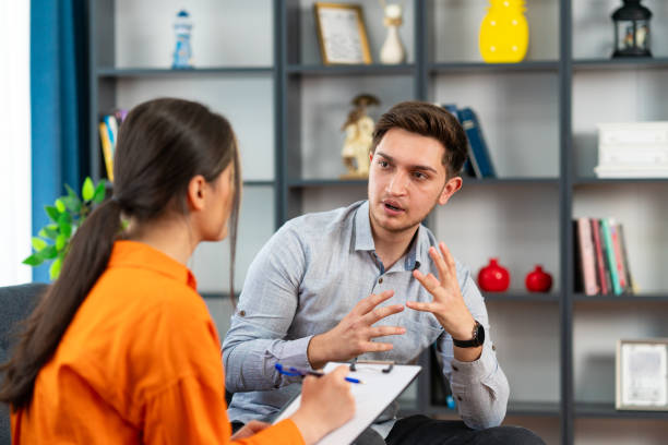 istock Handsome young man looking thoughtful while sitting in session with his female therapist 1581125546