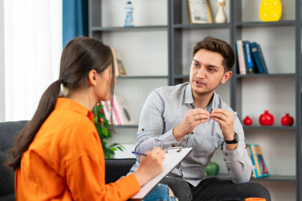 istock Handsome young man looking thoughtful while sitting in session with his female therapist 1581126592
