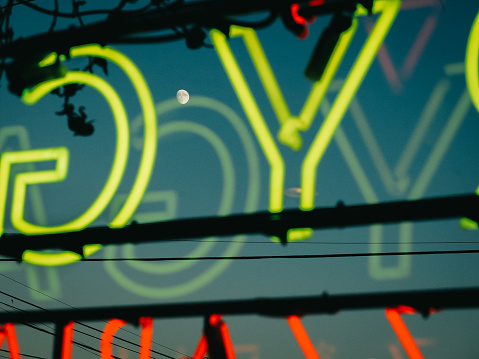 moon through vibrant neon sign on store window