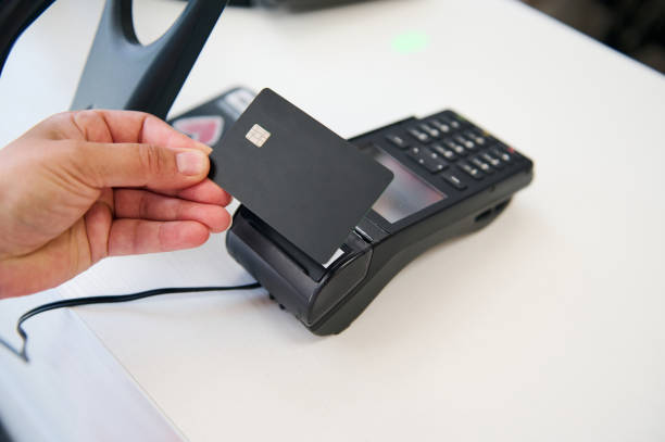 istock Close-up. Hand holding black mockup plastic card with copy ad space over a credit card reader, making cashless payment 1581154405