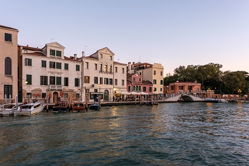 Venice, Italy – September 19, 2022: A picturesque scene of a river lined with boats of varying sizes, including small boats and houses, set against a peaceful landscape