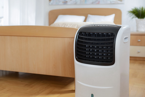 Portable mobile air conditioner stands in the bedroom at home, copy space