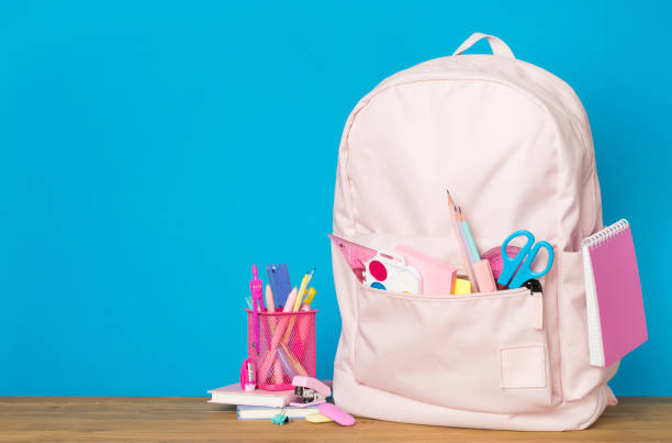 istock Pink school backpack with stationery on wooden table 1581239647