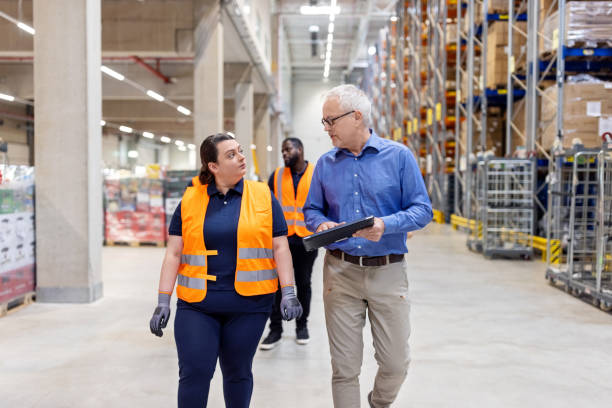 istock Mature manager using digital tablet and discussing stock with female worker in warehouse 1581299861