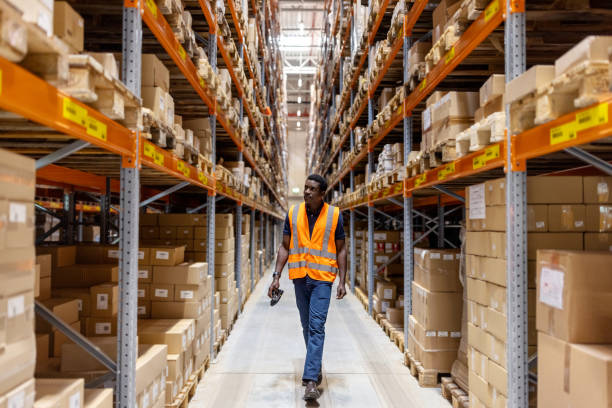 istock Male worker looking at cargo boxes on storage racks in large warehouse 1581299866