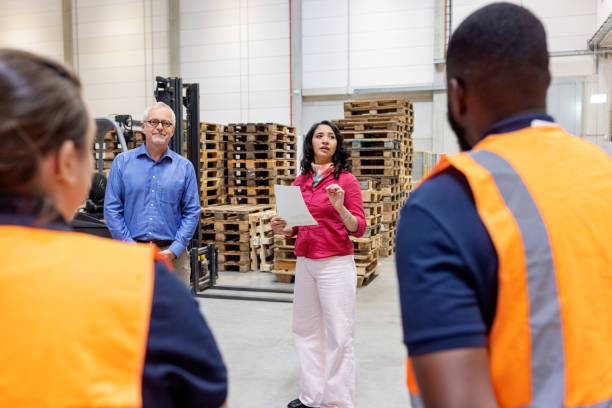 istock Mature woman manager talking with employees in distribution warehouse 1581299893