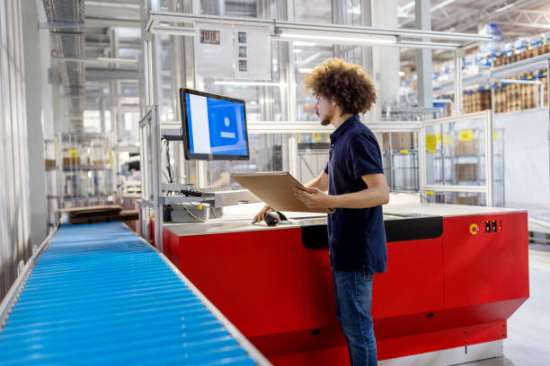 istock Male worker scanning a delivery package and working on computer at automated warehouse. 1581300023