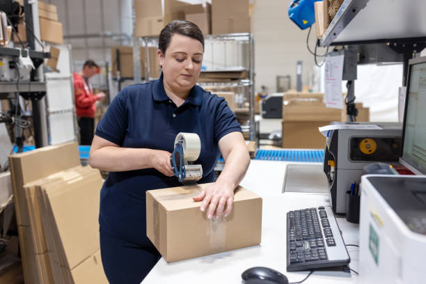 istock Woman working in distribution warehouse preparing a package for delivery 1581300412
