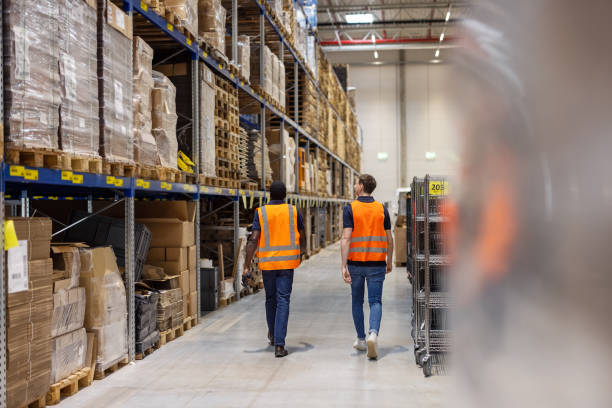 istock Two warehouse workers walking along the storage racks and checking inventory 1581309761