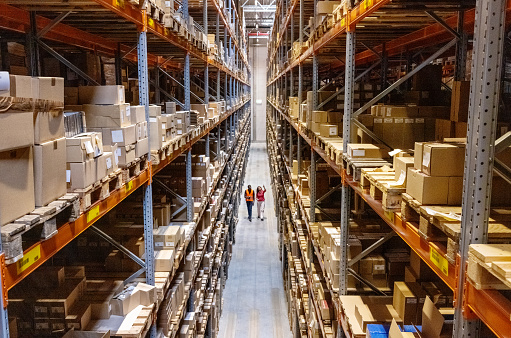 High angle view of a warehouse manager walking with foremen checking stock on racks