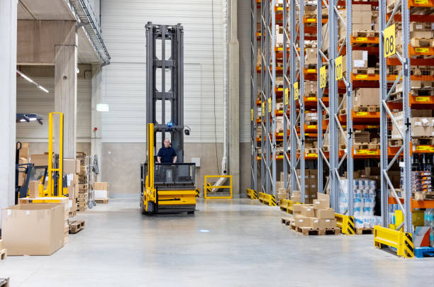 Large supply chain warehouse with forklift moving goods. Male worker operating forklift in a warehouse facility.