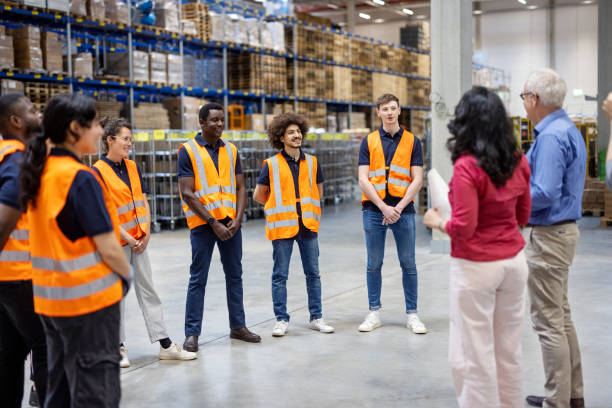 Mature businessman and businesswoman meeting with warehouse employees stock photo