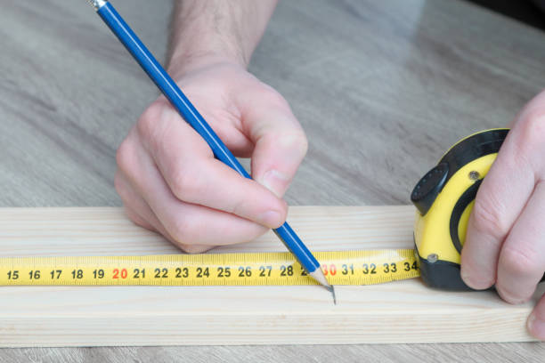 istock Carpenter hand measuring tape with pen in construction site. Making measurements with measuring tape and making marks with pen. 1581312190