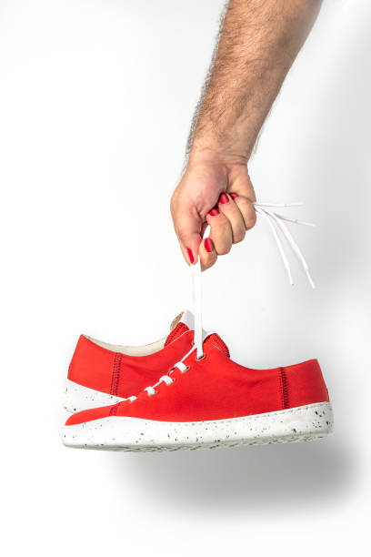 istock Male hand with red fingernails holding red sneakers 1581345879