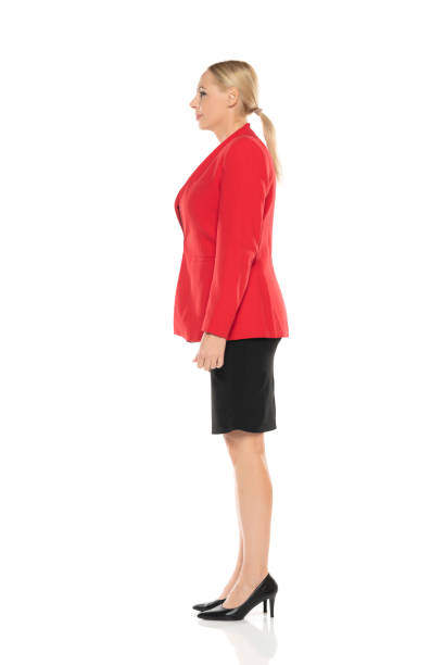 middle aged senior business woman in red jacket and black skirt posing on white studio background. side, profile view. - dress red high heels looking at view imagens e fotografias de stock
