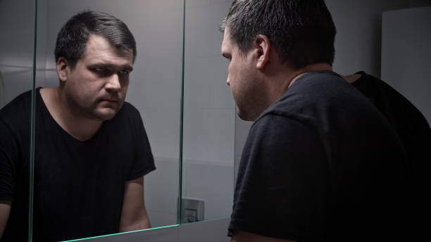 istock Young angry man breathing deeply and looking in his reflection in mirror. Concept of depression, suicide, stress, mental illness, loneliness and frustration. 1581394675