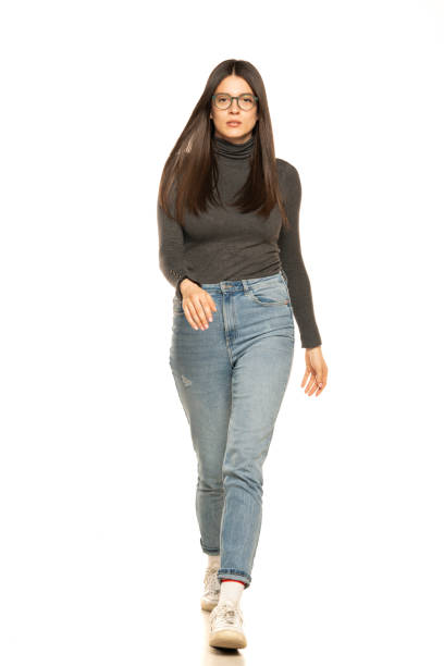 istock young beautiful woman in jeans walking on white 1581409983