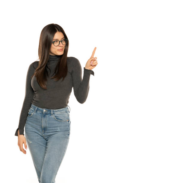 istock happy young and beutiful woman standing isolated over white wall background. She is showing copyspace pointing. Product placement 1581409989