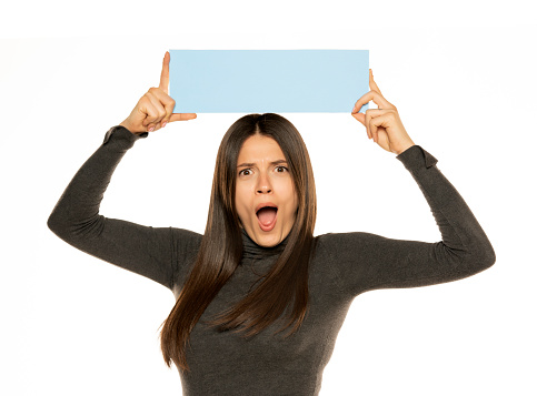 Beautiful excited woman holding a blank blue billboard isolated on white background