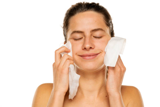 istock A young happy woman removing makeup with the wet tissues  on white background 1581428235