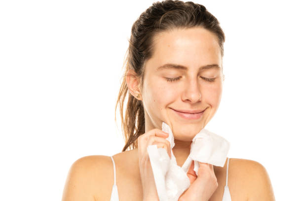 istock A young happy woman removing makeup with the wet tissues  on white background 1581428762