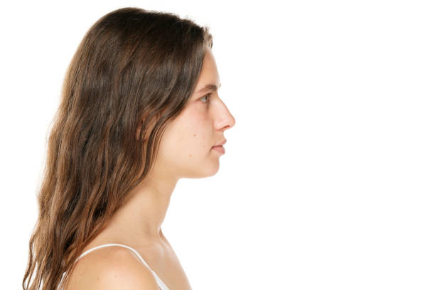 Close-up studio portrait of an attractive young white woman with brown ponytail hair against a white background