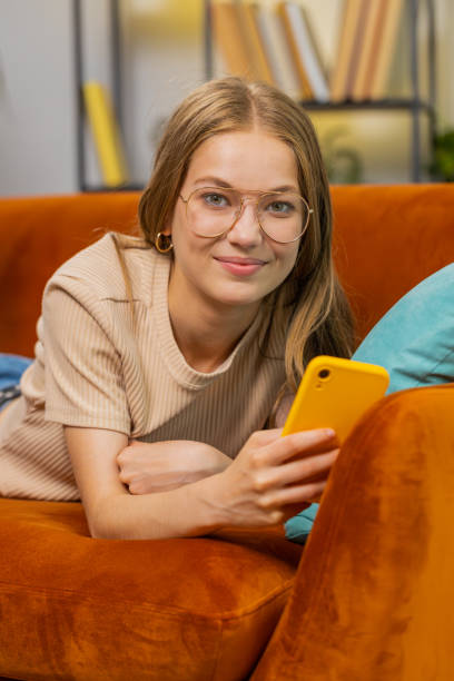 istock Young woman lying on sofa at home, using smartphone share messages on social media application 1581506079