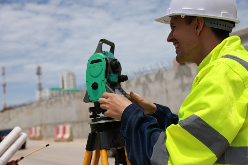 Male engineer or survey equipment working at the construction site with survey camera.