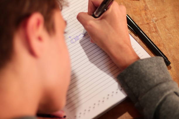 istock Focus on a Child's Hand Writing in his Notebook 1581520195
