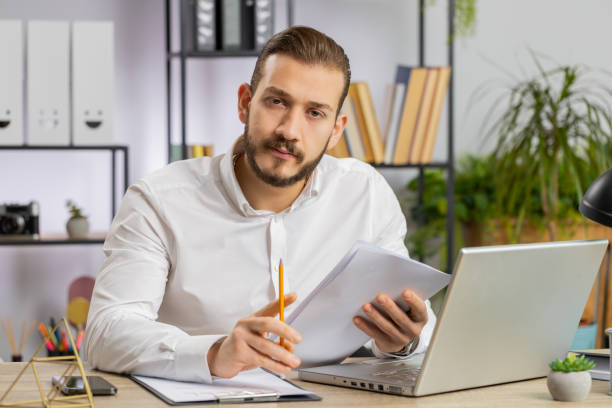 istock Business man reading business contract, planning project, analyzing resume, good paperwork results 1581536413